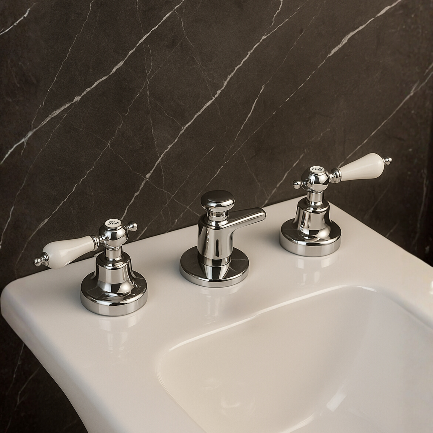 Chrome bathroom faucet with white handles on a sink against a dark marble wall.
