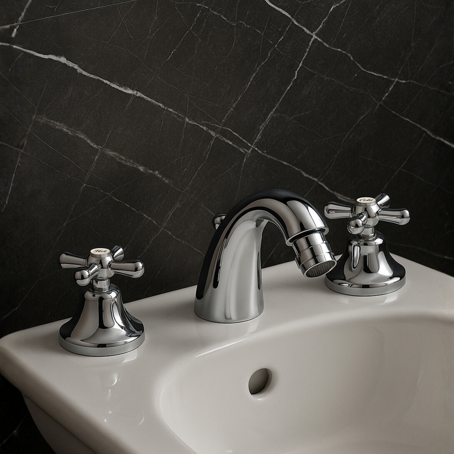 Chrome bathroom faucet and handles on a white sink against a black marble wall.
