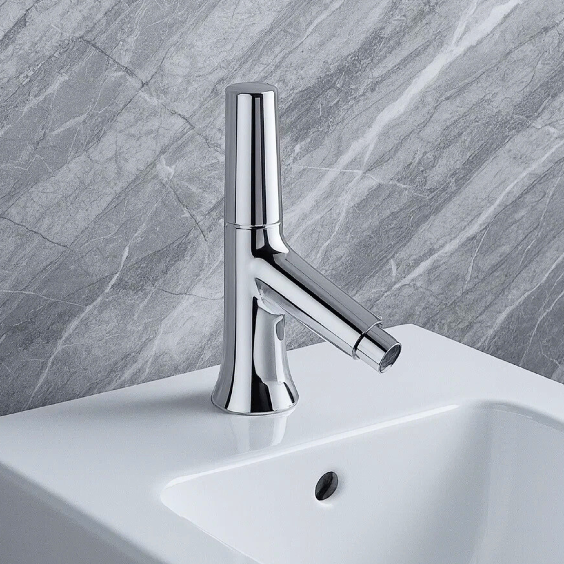 Chrome faucet on a white sink with a gray marble wall background
