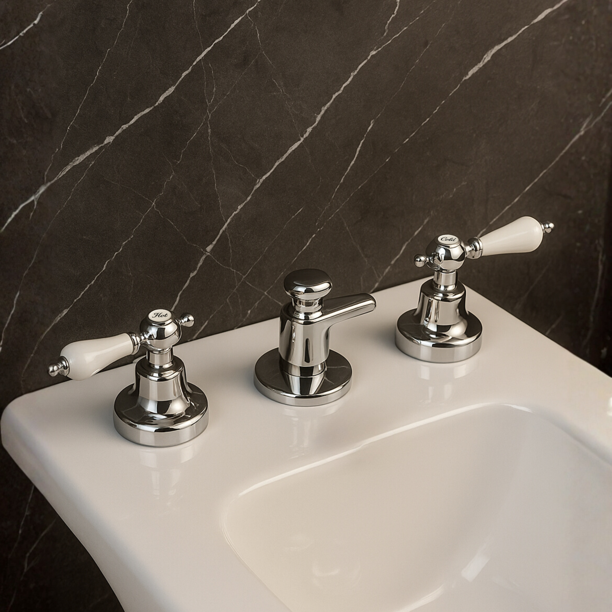 Chrome bathroom faucet with white handles on a sink against a dark marble wall.