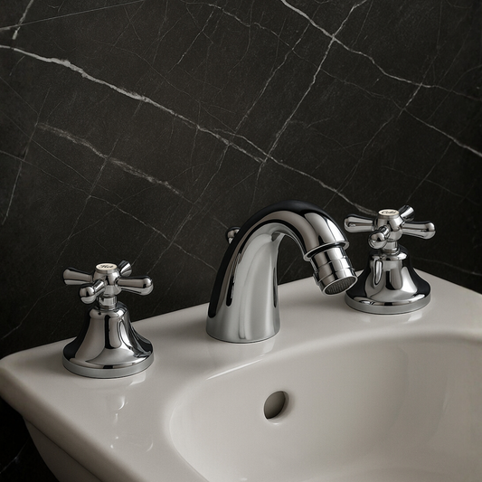 Chrome bathroom faucet and handles on a white sink against a black marble wall.