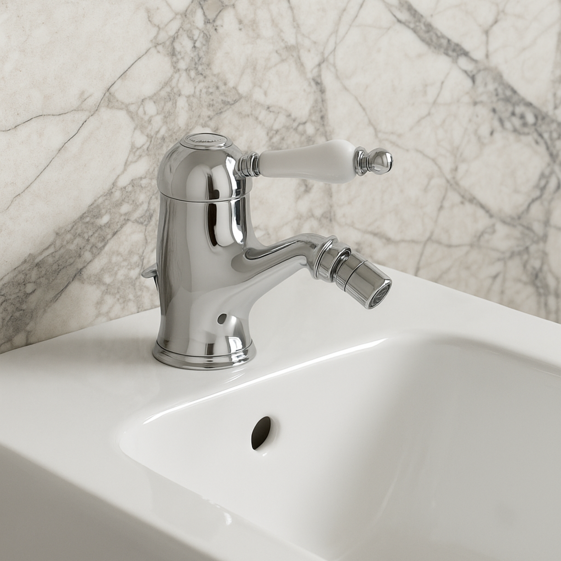 Chrome bathroom faucet on a white sink with a marble wall background
