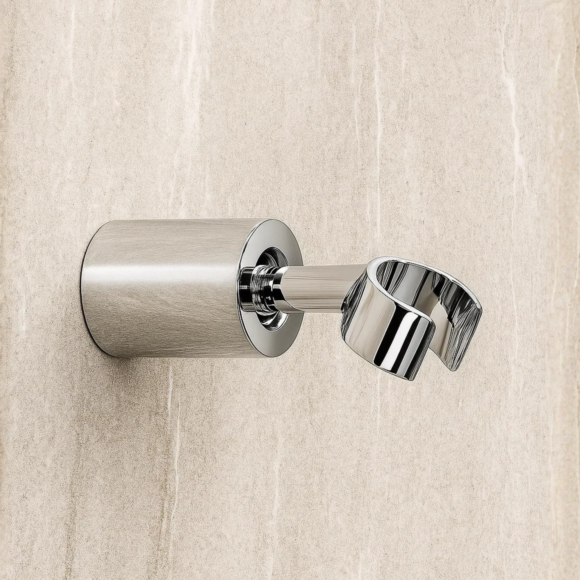 Metallic shower head holder on a textured beige wall